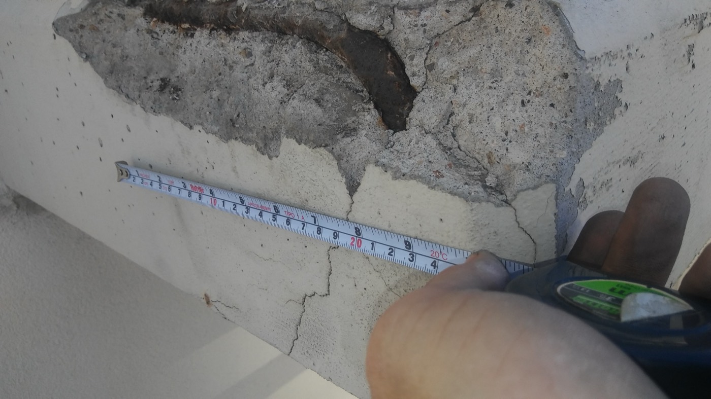 Technician measuring concrete spalling damage on commercial facade