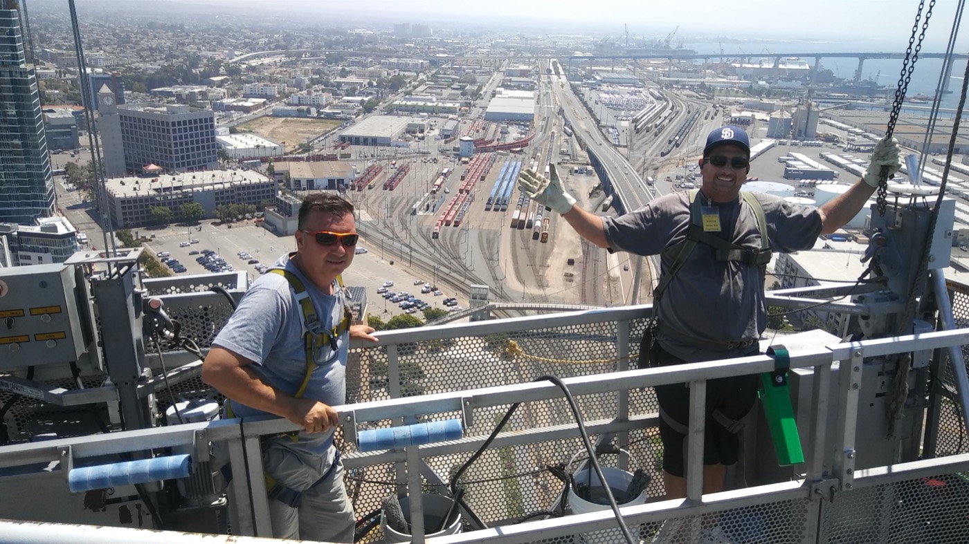 Rope access crew on the Omni Hotel rooftop, San Diego Bay behind them