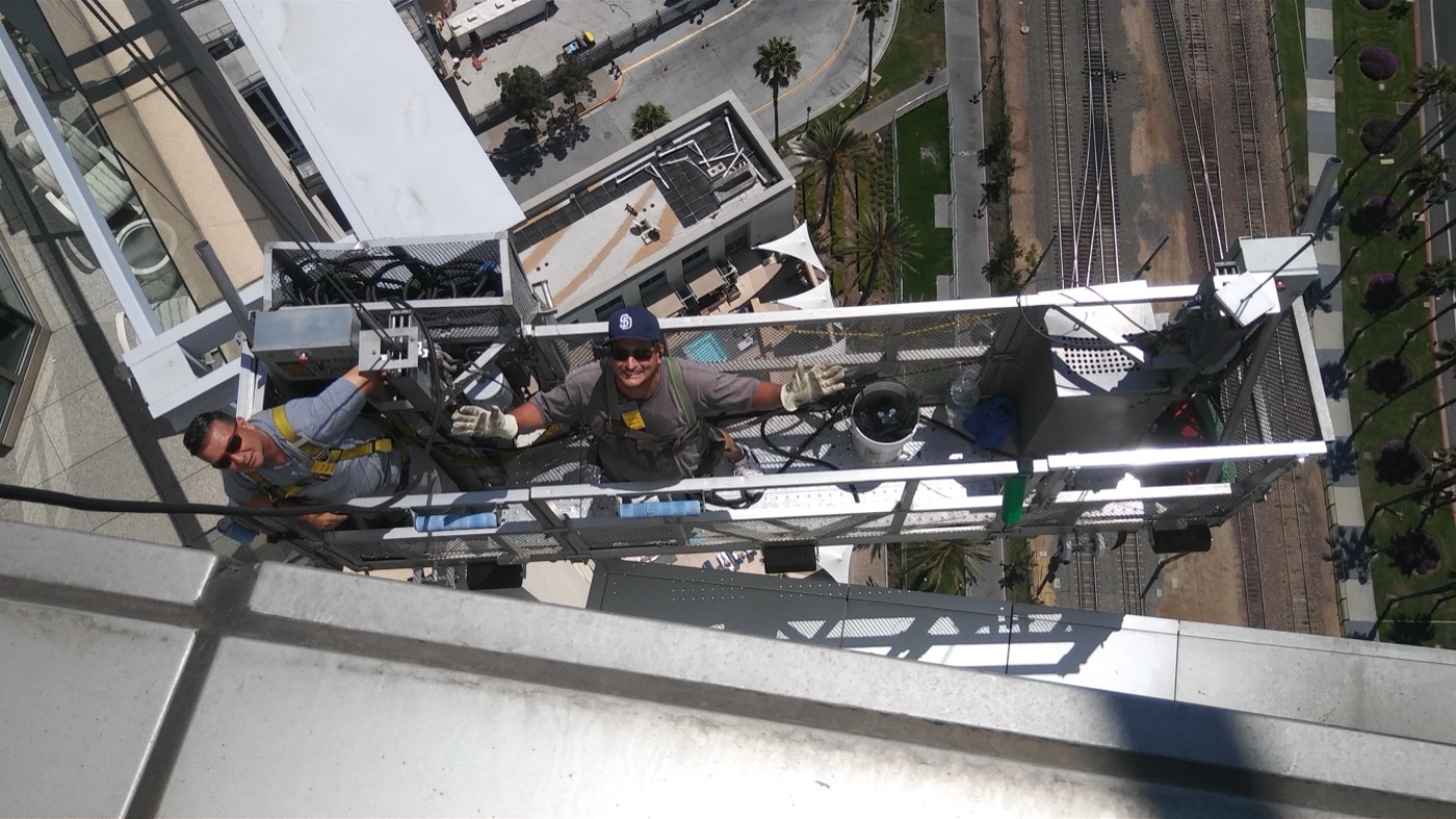 Two technicians on swingstage platform, San Diego street far below