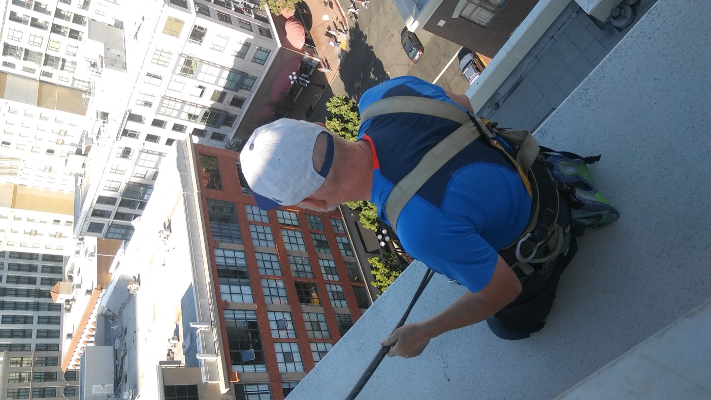 Technician rappelling down commercial high-rise facade