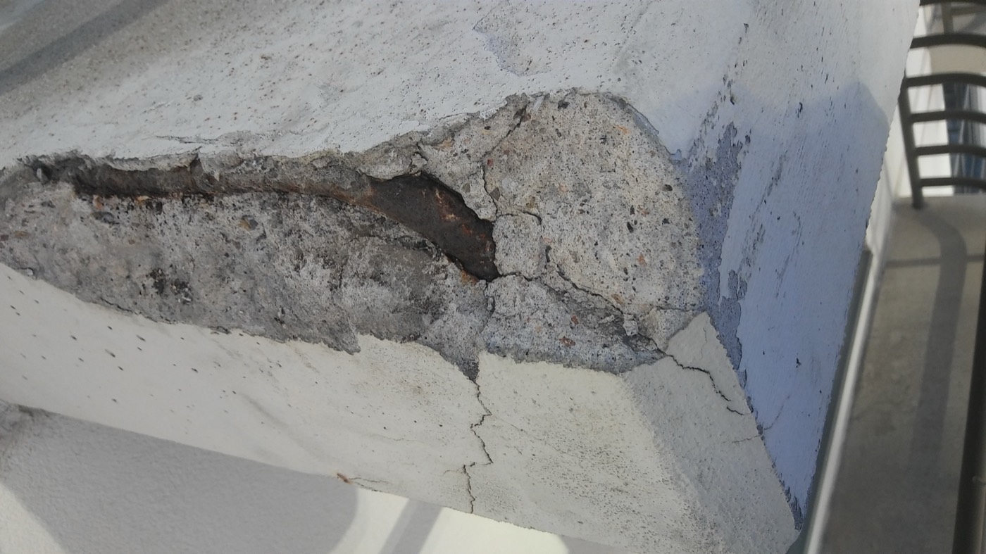 Concrete spalling and structural damage on a commercial facade